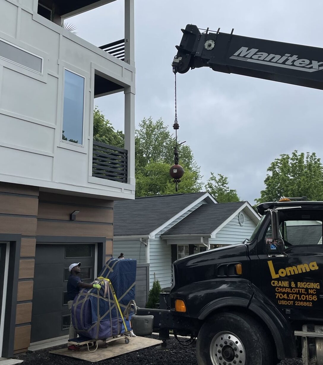 A crane hoists a piano onto a moving truck, illustrating the process of moving large structures with heavy equipment.